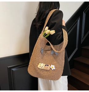 Détail du sac cabas en paille avec des écussons mignons et un nœud à carreaux bleus