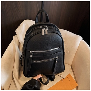 Close-up of black lychee-grain leather backpack featuring premium silver zippers and texture