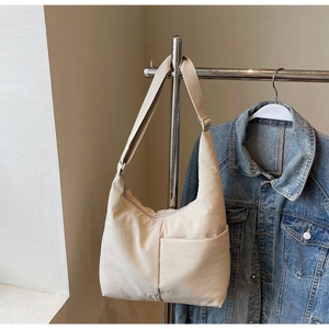 Detail of minimalist beige nylon tote bag with exterior pocket and wide shoulder strap