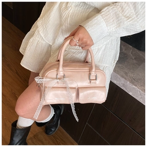 Detailed top view of pink handbag with lace bows and dual front pockets on dark wood