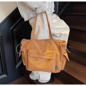 Detail of mustard yellow nylon tote bag featuring functional drawstring side pocket