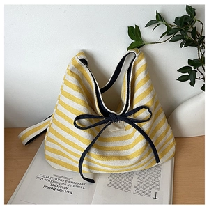 Close-up of striped canvas texture and black ribbon bow detail on the yellow tote bag