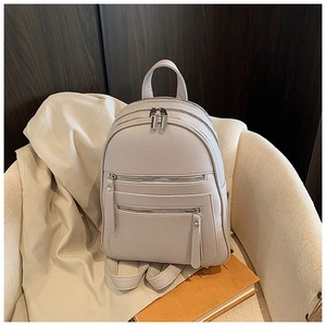 Detailed view of beige pebble grain texture and polished silver zippers on casual backpack