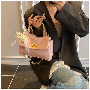 Detail view of pink crossbody bag with gold chain, lace bow and pearl charm