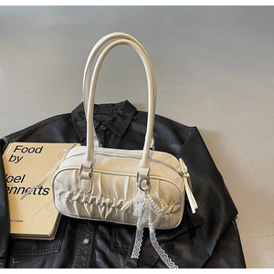Detail of creamy white pleated Boston bag with pearl lace charm on a black leather jacket