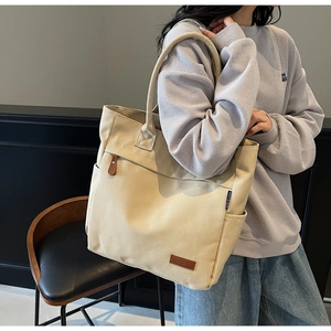 Detail of large canvas tote bag showing the KFRBAG leather logo and front zipper pocket