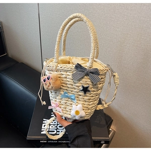 Détail du sac seau en paille tressée avec nœuds colorés et pendentif ours