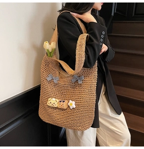 Détail d'un sac cabas en paille tissée avec des nœuds à carreaux et des écussons