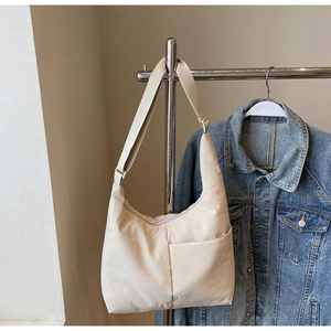 Detail of off-white nylon tote bag with side pocket and adjustable wide strap