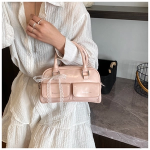 Close-up of pink Boston bag with white lace bow and embossed square pockets details