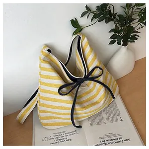 Detail of yellow and white striped canvas tote with dark blue bow and navy lining