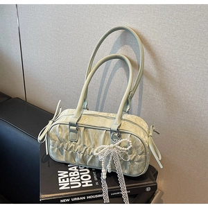 Detail of light green pleated handbag with pearl bow ribbon on urban housing book