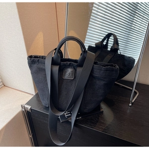 Détail du sac cabas en denim noir avec patch logo en cuir et design plissé sur le haut