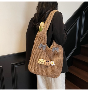Détail du sac cabas en paille kaki avec nœuds à carreaux et breloques oursons