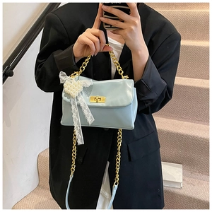 Detail of light blue crossbody bag with gold chain strap and lace pearl heart bow
