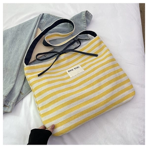 Detail of yellow striped canvas tote bag with a 'SEE YOU' patch and navy blue bow accent