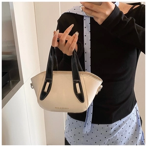 Detail of cream crossbody bucket bag with black handles and white contrast stitching