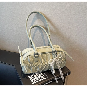 Detail of light green pleated handbag featuring pearl bow pendant and lace decoration