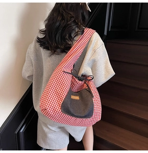 Detail of red gingham tote bag featuring a denim pocket and leather patch on stairs