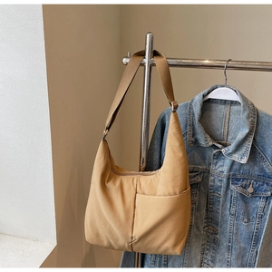 Close-up of the khaki nylon crescent bag with adjustable strap hung by a denim jacket