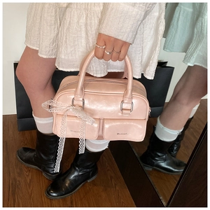 Detailed shot of a pink Boston bag with lace bows and decorative flap pockets