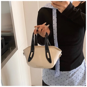 Detail of off-white bucket bag with black handles, white stitching and side D-rings