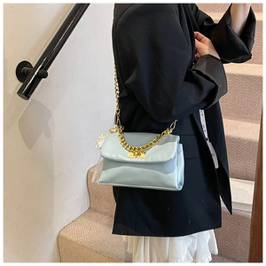 Detail view of the light blue square bag with gold chain and twist lock on a model