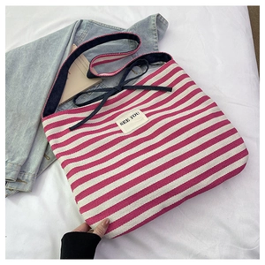 Detail of pink and white striped canvas tote bag with See You patch and blue shoulder strap