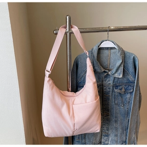 Pink nylon hobo bag featuring adjustable wide strap and side slip pocket detail
