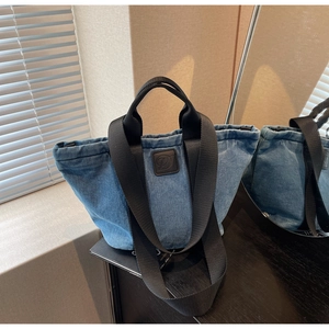 Gros plan détaillé du sac cabas en jean bleu avec anses noires et écusson en cuir