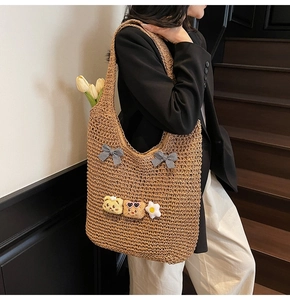 Détail du sac cabas en paille tressée avec nœuds à carreaux et pendentifs en peluche