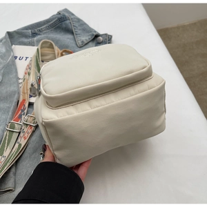 Detail of cream nylon backpack with floral patterned shoulder strap and silver hardware
