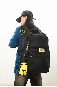 Detail view of mini black crossbody bag with yellow accents and a small zipper pendant