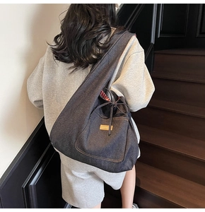 Detail of large denim hobo bag showing wide strap and red gingham lining texture