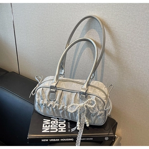 Detail of silver pleated bowling bag featuring pearl lace charm and ribbon bow accents