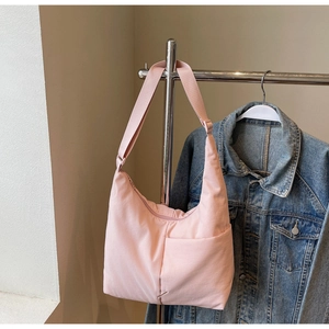 Macro shot of light pink nylon crescent bag with adjustable strap and front pocket