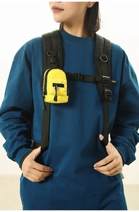Close-up of bright yellow mini nylon shoulder bag with black zippers on a blue sweatshirt