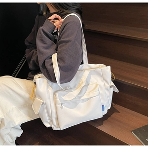 Detail of white large capacity tote bag featuring multi-pocket design and yellow drawstrings