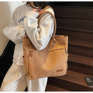 Close-up of canvas tote bag with front zipper pocket and KFBAG label on wooden stairs
