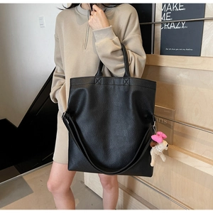 Detalle de bolso tote de cuero granulado negro con colgante de perro decorativo