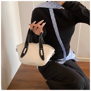 Detail of a chic cream white bucket bag with black handles and metal D-rings