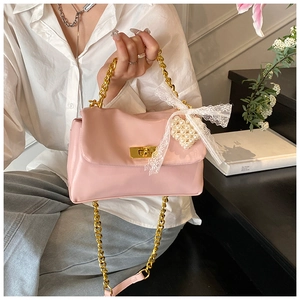 Detail of pink PU leather handbag with gold rotating lock, lace bow and pearl heart charm