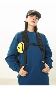 Mini yellow nylon pouch with zipper and clip attached to a black backpack strap