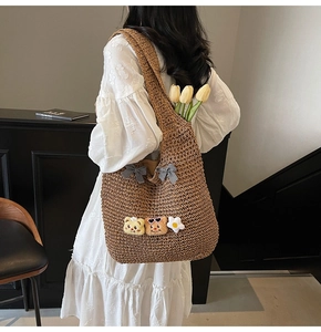 Détail du sac cabas tressé avec des nœuds à carreaux noir et blanc et des charms en peluche