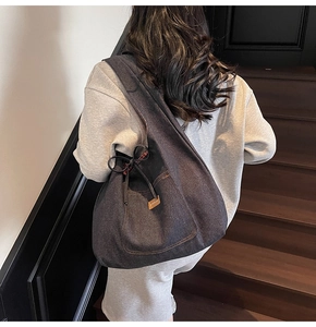 Detail of a navy denim tote bag with drawstring closure and plaid lining on wooden stairs