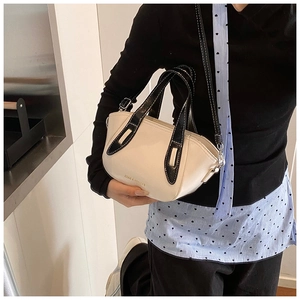Close-up of cream leather bucket bag with black trim and FASHION & BAGS gold lettering