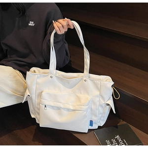 Detail of white tote bag with zipper front pocket and yellow drawstring on wooden stairs