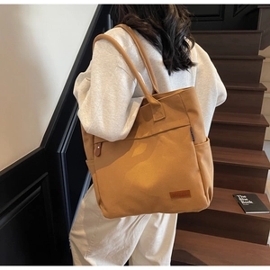 Close-up of khaki canvas tote bag with leather logo tag and practical side pocket detail