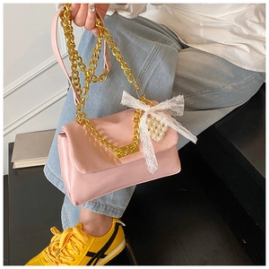 Detail view of pink square shoulder bag with gold chain, lace bow, and pearl charm