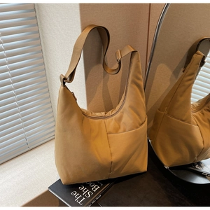 Close-up of lightweight khaki nylon tote bag showing side pocket and adjustable strap
